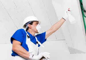 worker spraying ceiling with spray bottle
