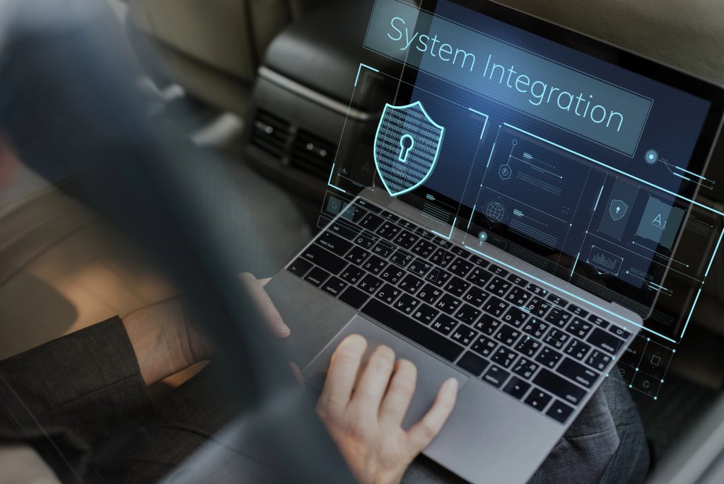 Businessperson typing on laptop keyboard, with the word 'Systems Integration' on screen