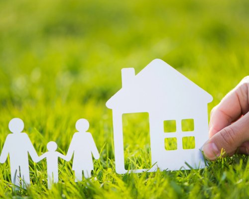 Paper cut family with house in green grass background