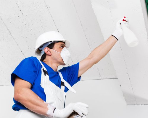 worker spraying ceiling with spray bottle