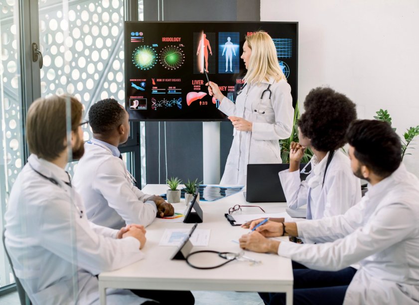 Group of doctors sat around a table, looking at a screen, showing patients information